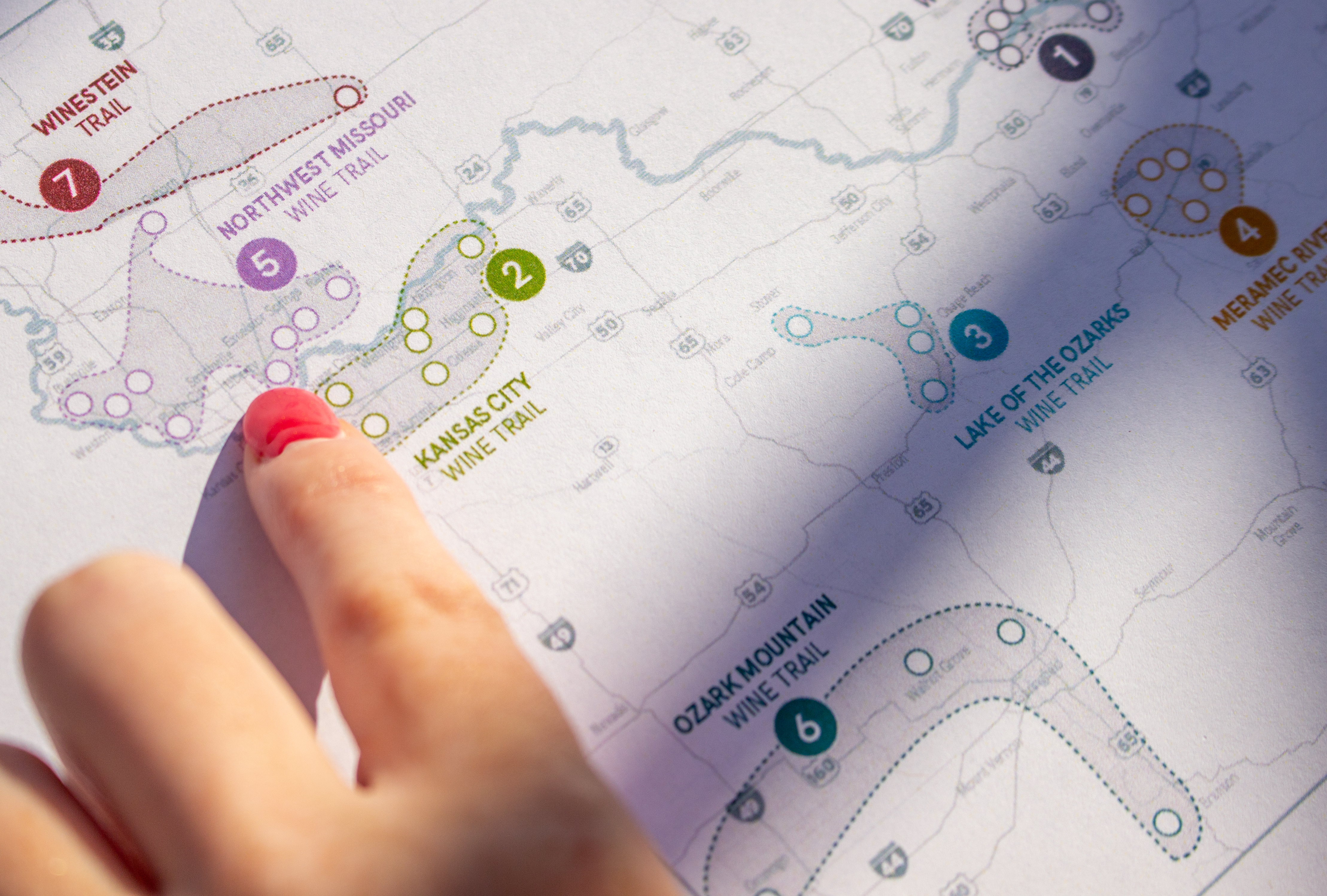 A finger pointing to a wine trail on the map