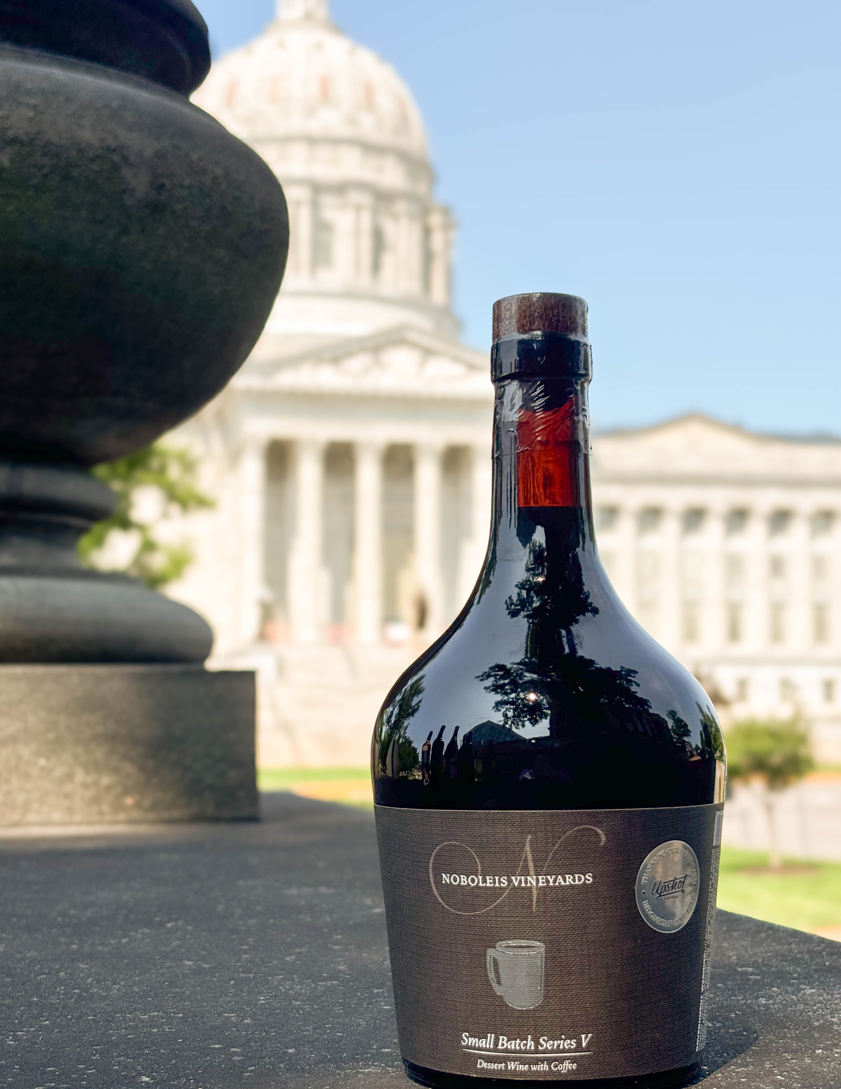 Wine bottle sitting on ledge in front of capital