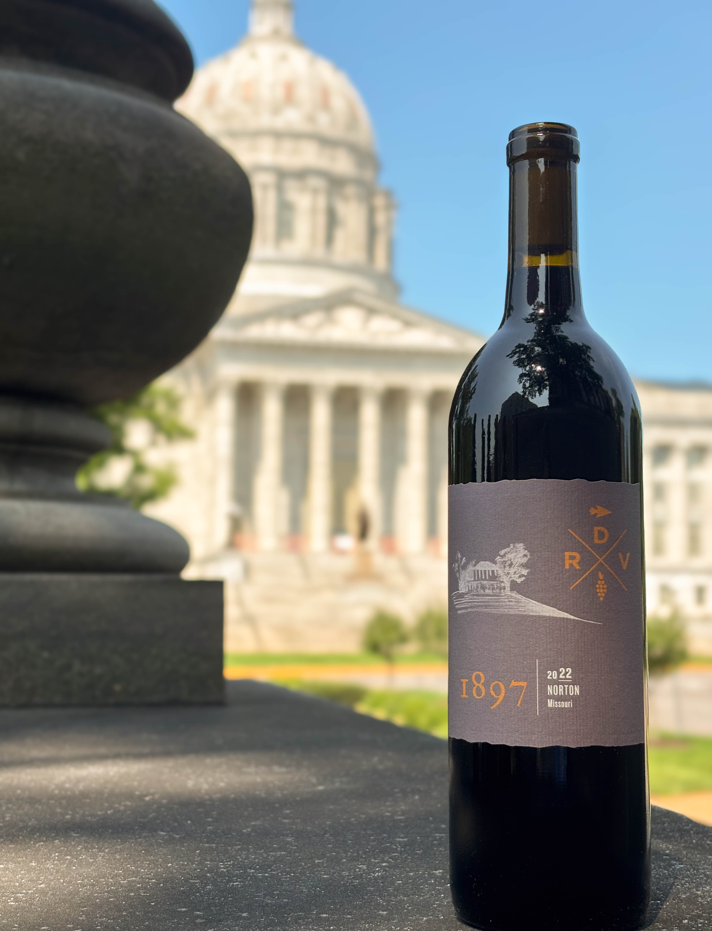 Wine bottle sitting on ledge in front of capital