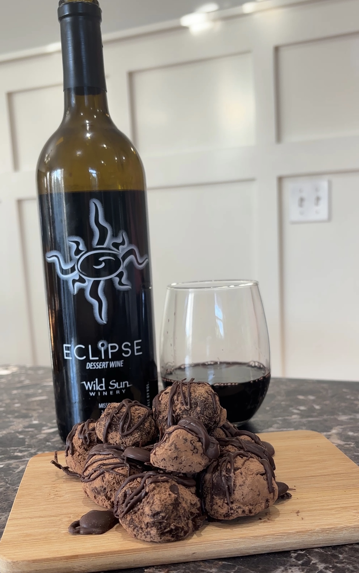 a glass and bottle of port wine and chocolate truffles sitting on a cutting board