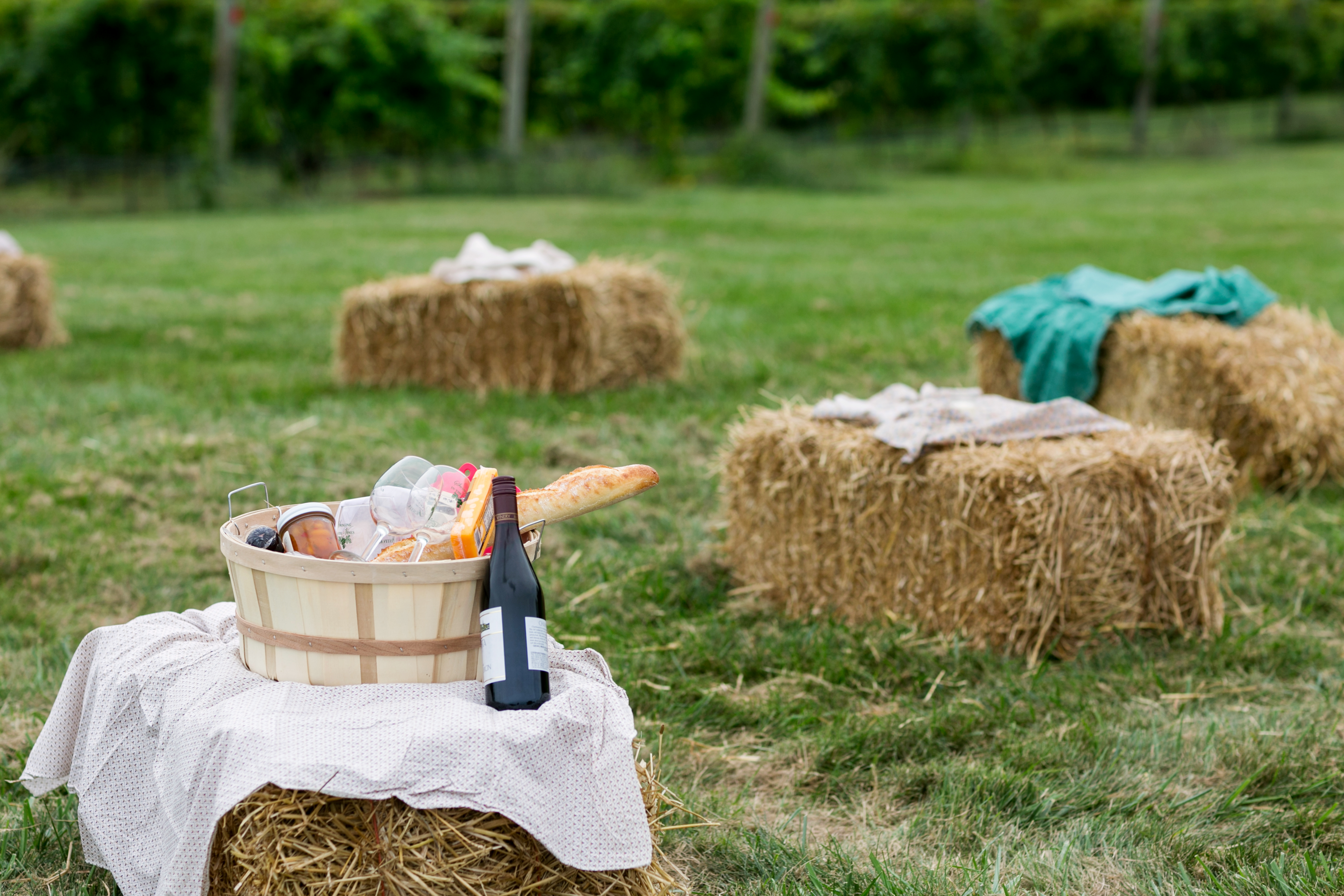 Text overlayed an image with a strawbale in the front with a basket of food items and wine.
