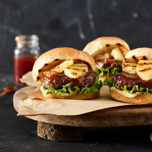 beef sliders with pineapple on parchment paper